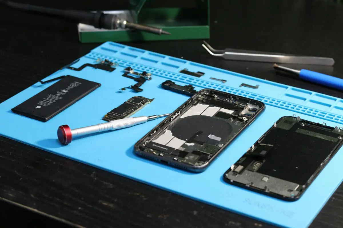 Szétszerelt iPhone: kijelző, akkumulátor és alaplap a javítóalátéten